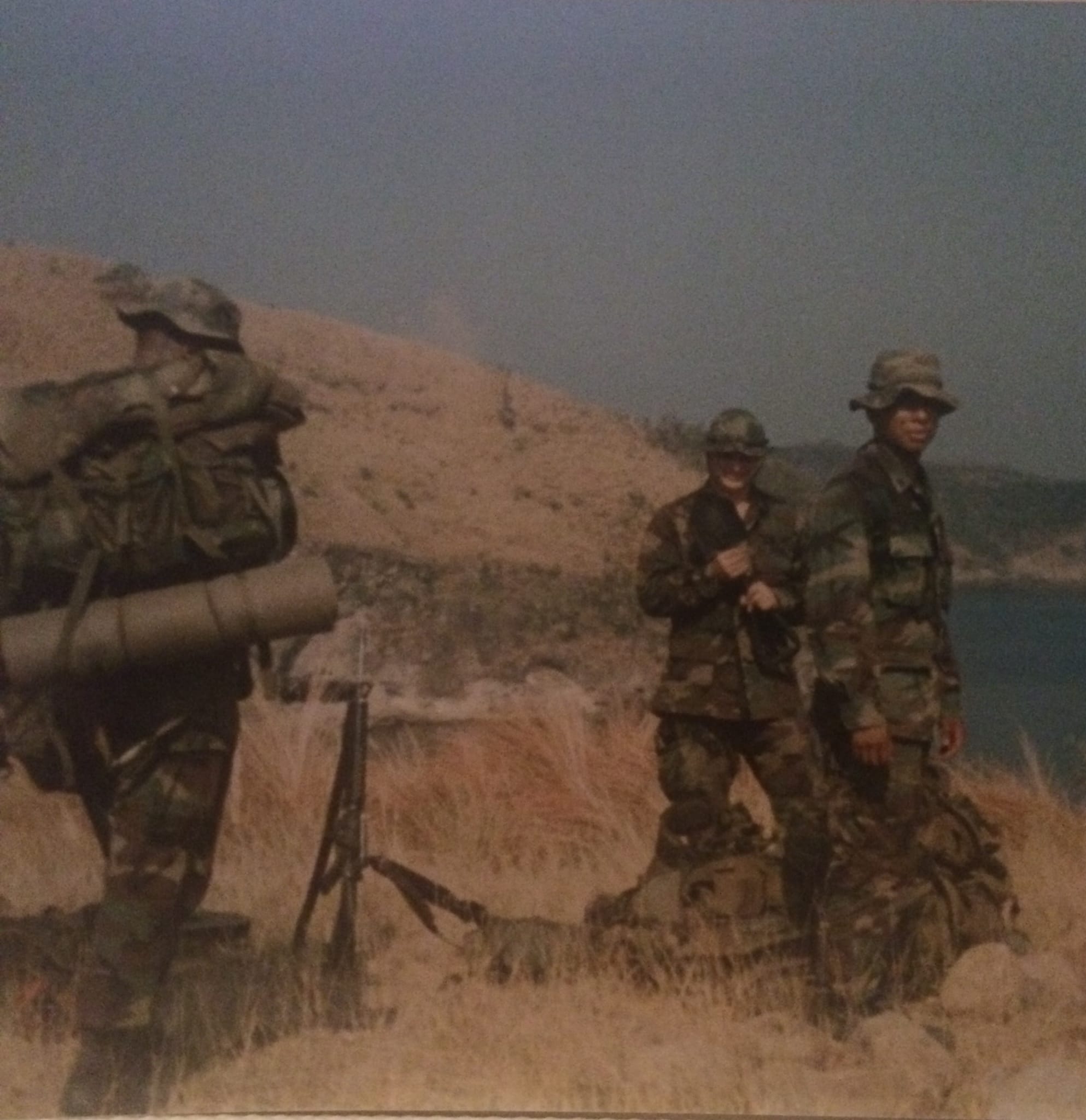 Marines with heavy packs during field training on coastal terrain